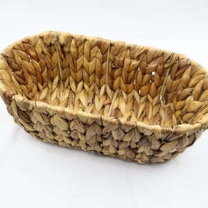 May include: A woven oval basket made of natural materials, perfect for storing small items or displaying decorative objects.