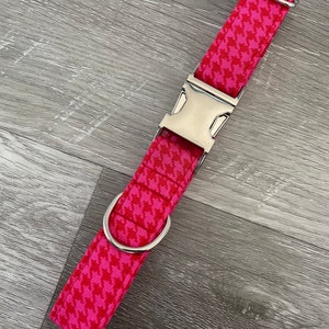 K&ouml;nnte beinhalten: Ein pinkfarbenes und wei&szlig;es Hundehalsband mit Hahnentrittmuster, silberner Schnalle und D-Ring.