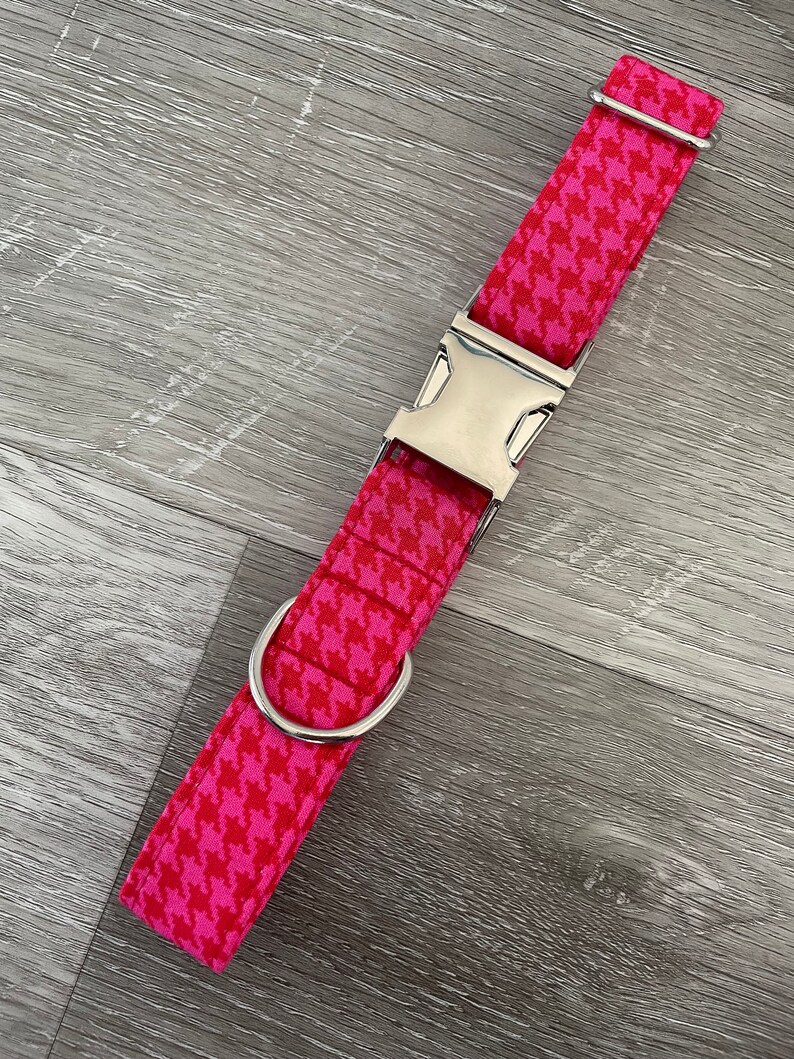 K&ouml;nnte beinhalten: Ein pinkfarbenes und wei&szlig;es Hundehalsband mit Hahnentrittmuster, silberner Schnalle und D-Ring.