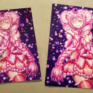 以下が含まれることがあります： ピンク色の、長い三つ編みの髪と桜の装飾が施された、アニメスタイルのキャラクターが描かれた2つのアートプリント。キャラクターはピンク色のドレスを着ており、白い花が散りばめられた濃い紫色の背景が特徴です。