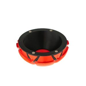 May include: A red and black bowl with a geometric design. The bowl has a black interior and a red exterior with black accents. The bowl is made of a durable material and is perfect for holding small items.