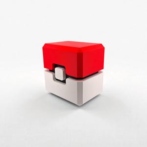 May include: A red and white geometric cube-shaped object with a black accent. The top section is red, the middle is black, and the bottom is white. The object has a rectangular shape with a small square indentation.