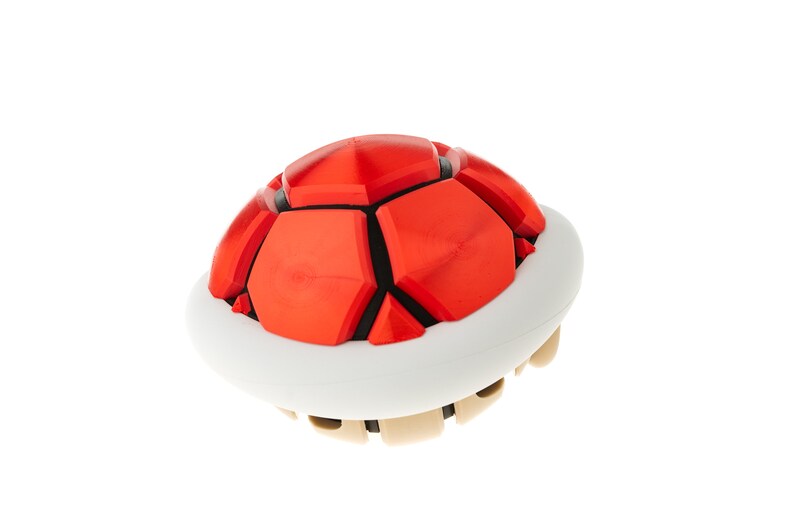 May include: A red and white plastic toy shell, resembling a turtle shell, with a textured surface.