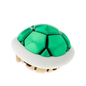May include: A green and white plastic shell, resembling a turtle shell, from the popular video game Super Mario Bros.