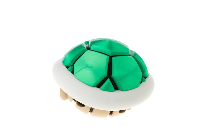 May include: A green and white plastic shell, resembling a turtle shell, from the popular video game Super Mario Bros.