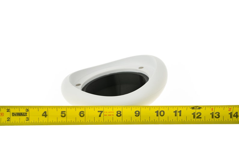 May include: White plastic speaker enclosure with a black speaker grill. The enclosure is about 6 inches wide and 3 inches tall. A tape measure is visible below the enclosure.