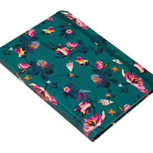 May include: A teal blue notebook with a floral pattern featuring pink, yellow, and white flowers. The notebook has a matching elastic closure.