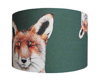 May include: A green lampshade featuring a white and orange fox print. The fox has its eyes closed and is looking to the right.