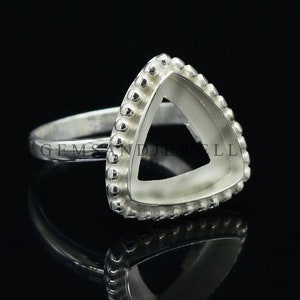 May include: Silver ring with a triangular bezel setting. The bezel is decorated with small beads around the edge. The ring is designed to hold a gemstone or cabochon.