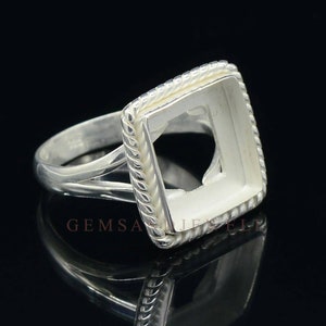 May include: Silver ring with a square bezel setting. The bezel has a rope-like design around the edge. The ring is designed to hold a gemstone.