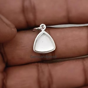 Op de afbeelding: Een zilveren driehoekige hanger met een witte steen in het midden. De hanger hangt aan een zilveren ketting.