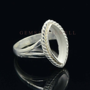 May include: Silver ring setting with a rope-like edge and a marquise-shaped opening for a gemstone. The ring is designed to hold a gemstone in place.