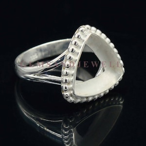 May include: Silver ring with a triangular bezel setting. The bezel is surrounded by a row of small beads.