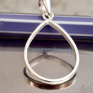May include: A polished silver pendant in a teardrop shape. The pendant has a loop at the top for a chain. The pendant is displayed on a reflective surface. The text "Gemsandjewell" is visible on the surface.