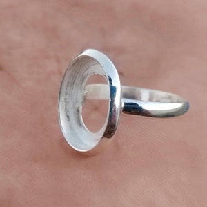 May include: Silver ring with a round bezel setting for a stone or cabochon.