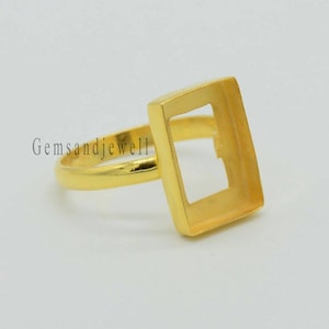 May include: Gold-toned ring with a square bezel setting. The ring is designed to hold a square-shaped stone or cabochon.