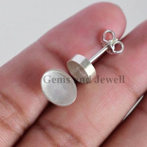 May include: A pair of silver earring settings with a round bezel. The settings are designed to hold a stone or other embellishment.