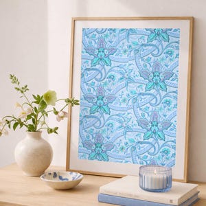 May include: A framed print with a light blue floral pattern, featuring teal and purple accents. The print is displayed on a wooden surface, alongside a vase with flowers, a small bowl, and a candle in a glass holder.