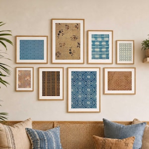 May include: A gallery wall arrangement featuring eight rectangular framed prints with light wood frames. The artwork displays various patterns including blue geometric designs, brown floral motifs, and striped textures, all displayed on a plain wall.