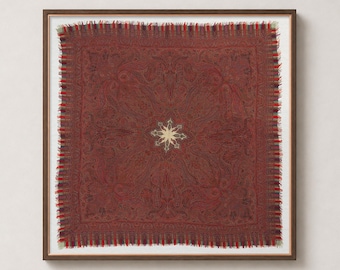 May include: A square textile piece framed in dark wood, featuring a deep red base with intricate, dark-toned paisley patterns and a central cream-coloured star motif. The edges are finished with a multi-coloured fringed border in red and blue.