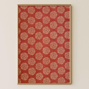 Red antique Indian block print floral artwork with repeat folk floral medallion pattern in vermillion and beige tones in a sleek wood frame on a soft warm cream wall