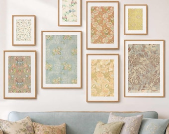 May include: A selection of framed floral art prints in various sizes and colours, including peach, yellow, and blue. The prints feature vintage-style floral patterns and are displayed above a blue sofa with matching floral cushions. The frames are a warm brown colour.