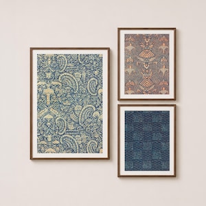 May include: Three framed wall art prints featuring intricate patterns. The large left print displays a blue and cream paisley design. The top right print shows a symmetrical geometric pattern in peach and blue. The bottom right print features blue grid-like motifs.