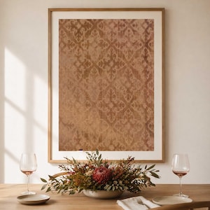 May include: A framed artwork with a brown and beige damask pattern hangs above a table. A floral centerpiece with red and green accents sits in a gray bowl. Wine glasses and plates are set on the wooden table.