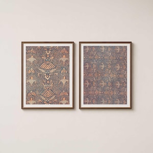 May include: Two rectangular wall art prints in dark brown frames. Each print features a repeating pattern of stylized bird-like figures and geometric shapes in shades of copper and orange against a dark navy blue background with fine white dots.