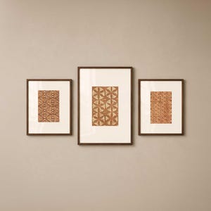 May include: Three framed art prints with brown wooden frames. The prints feature abstract patterns in shades of brown and beige. The artwork is displayed against a neutral-colored wall, creating a cohesive and stylish aesthetic.