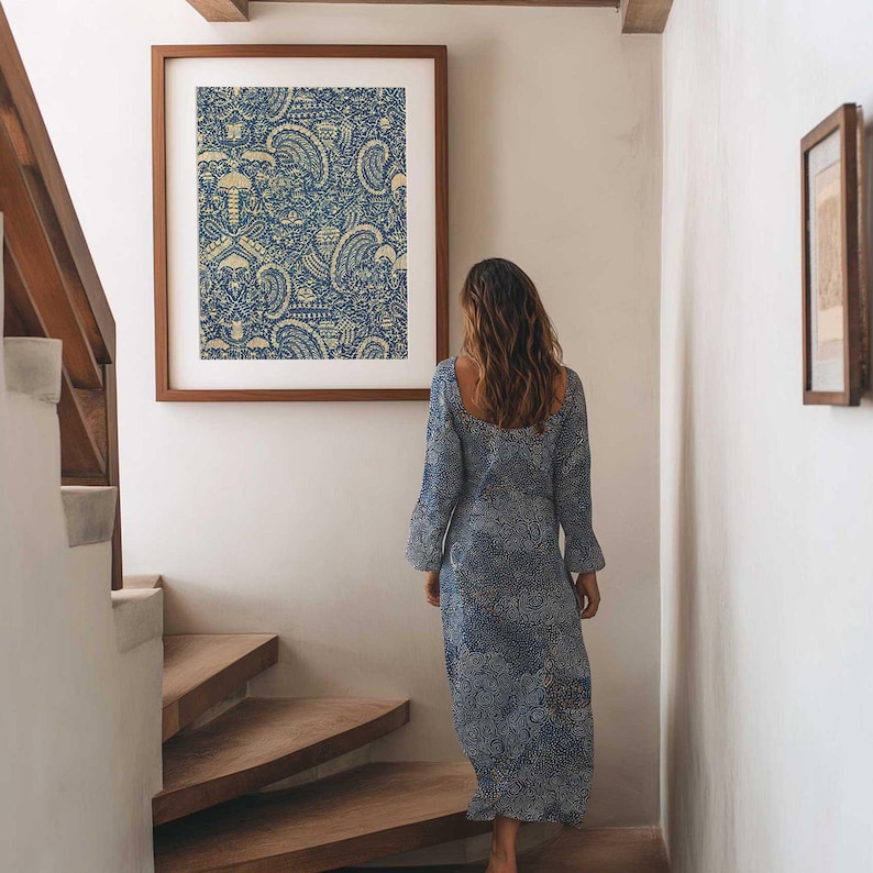 Indonesian Batik Fabric wall art featuring a blue tribal crayfish pattern hangs on the wall in a stairwell as a boho dressed woman walks past.