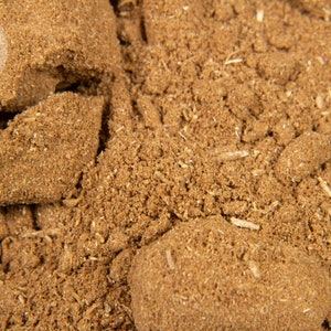 Può includere: Primo piano di un mucchio di polvere marrone e granulosa con una consistenza ruvida. La polvere sembra essere un prodotto naturale, forse una spezia o incenso. Il logo "The Agarwood Shop" è visibile in alto a sinistra.