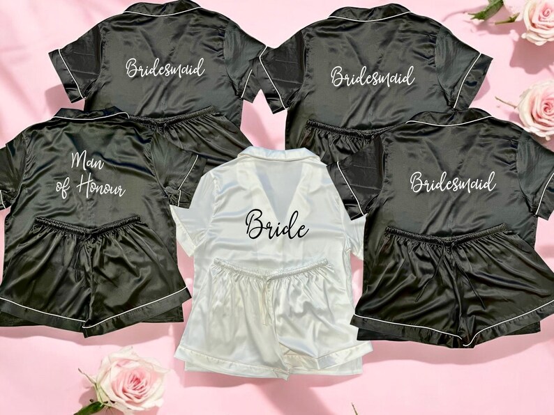 May include: Five black satin pajama sets with short sleeves and shorts. The sets have white embroidery that reads "Bride", "Maid of Honor", and "Bridesmaid".