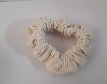 May include: A white, fluffy scrunchie made of soft, textured fabric. The scrunchie is in the shape of a circle and is perfect for holding hair in place.