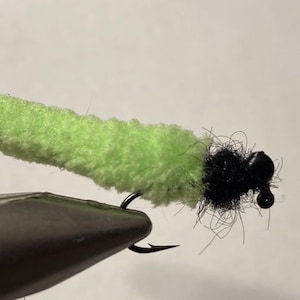 May include: A lime green fly tying material with a black bead head. The material is made of a fuzzy, fluffy material.