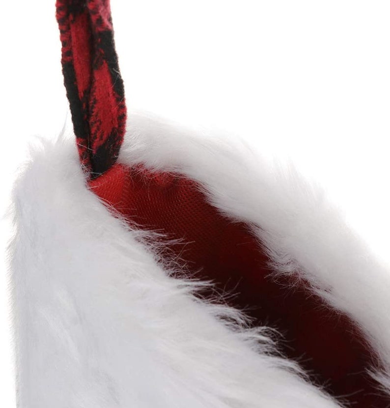 May include: A white faux fur stocking with a red and black plaid cuff. The stocking is lined with red fabric.
