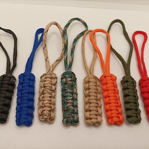Puede incluir: Un conjunto de siete tiradores de cremallera de paracord en varios colores: negro, azul, beige, camuflaje verde, beige, naranja, verde oliva y rojo. Cada tirador presenta un diseño trenzado y un lazo para sujetar.