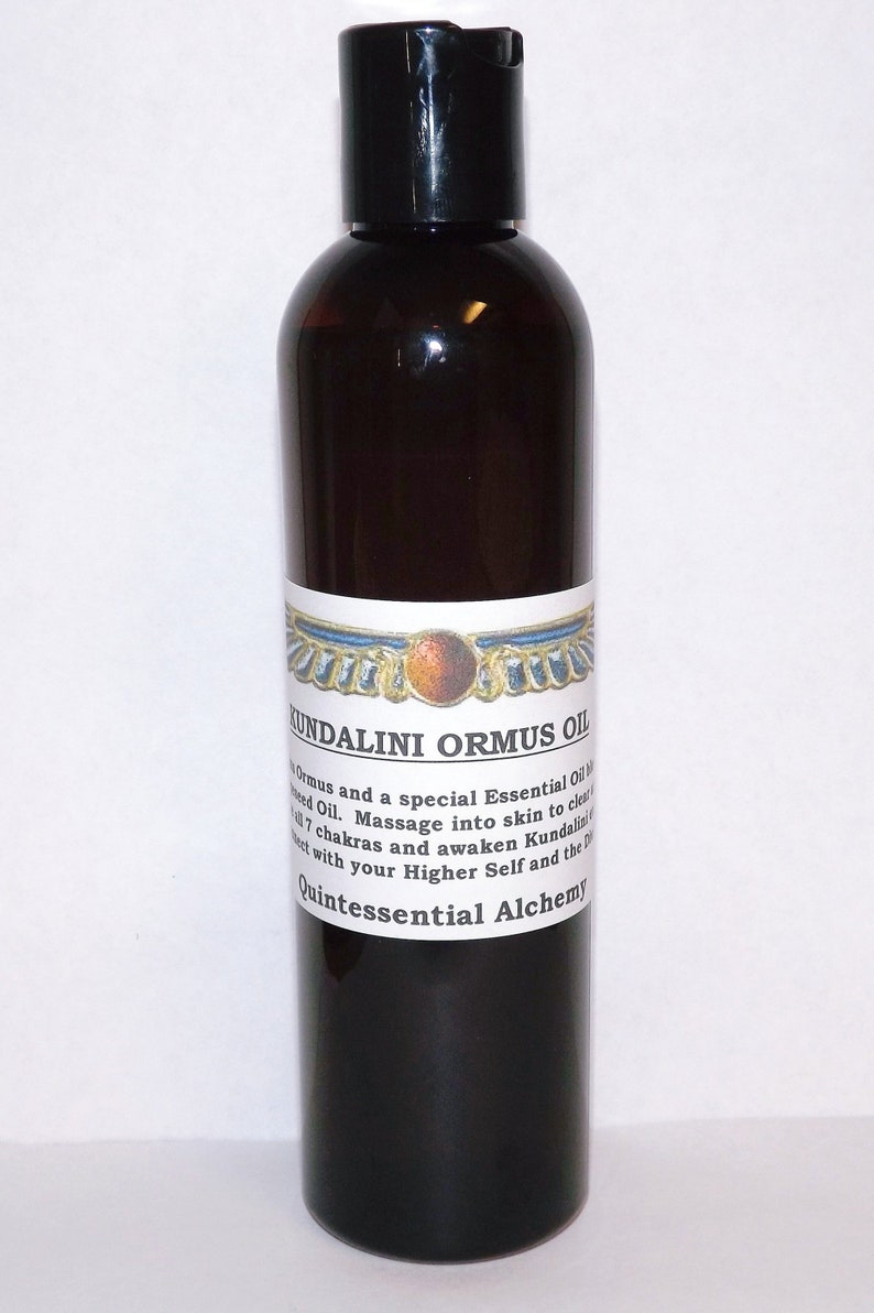 May include: A dark brown glass bottle with a black cap, labeled "Kundalini Ormus Oil". The label also includes a winged sun symbol and the text "Quintessential Alchemy".
