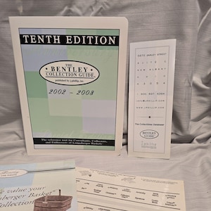 Puede incluir: Se muestra la Décima Edición de The Bentley Collection Guide, publicada por j.phillip, Inc. de 2002 a 2008. Una tarjeta más pequeña muestra información de contacto, incluida una dirección y un número de teléfono. También se ven materiales impresos adicionales.