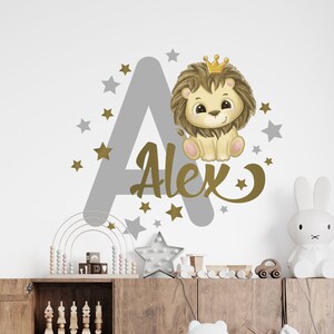 May include: A gray letter A with gold stars and a gold crown on top. A cute cartoon lion wearing a gold crown is sitting on the letter. The name Alex is written in gold letters below the lion.