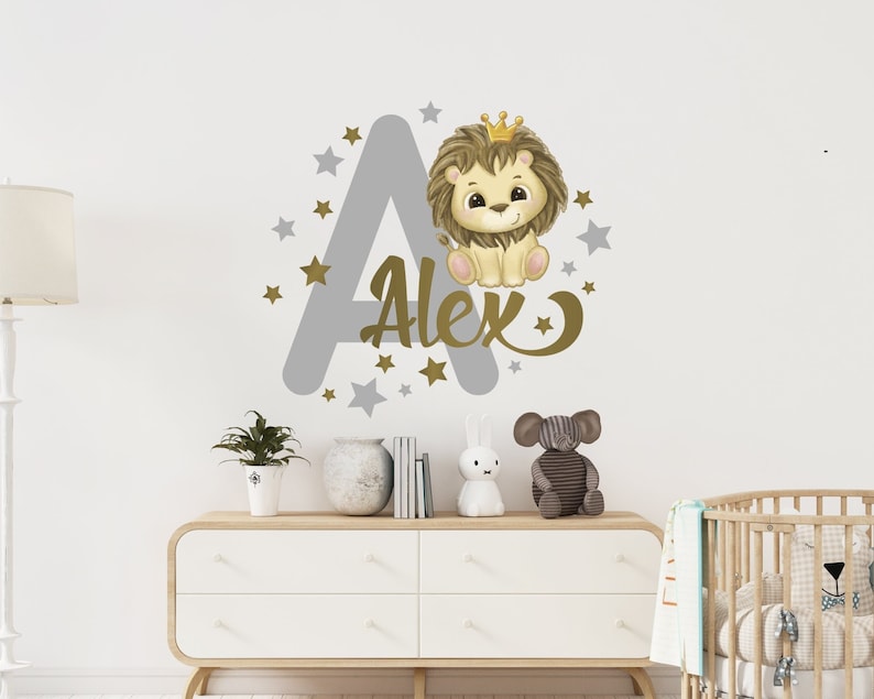 May include: A gray letter A with gold stars and the name Alex written in gold script. A cute cartoon lion wearing a gold crown sits on top of the letter A.