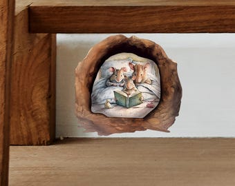 May include: A watercolour illustration depicts a family of mice inside a walnut shell. The mice are in bed, with one reading a book. The artwork uses soft colours and has a cosy, storybook aesthetic.