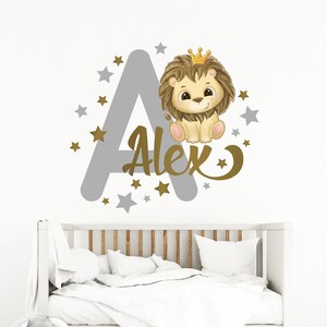 May include: A gray letter A with gold stars and a gold crown on top. A cute lion wearing a gold crown is sitting on the letter. The name Alex is written in gold cursive letters below the lion.
