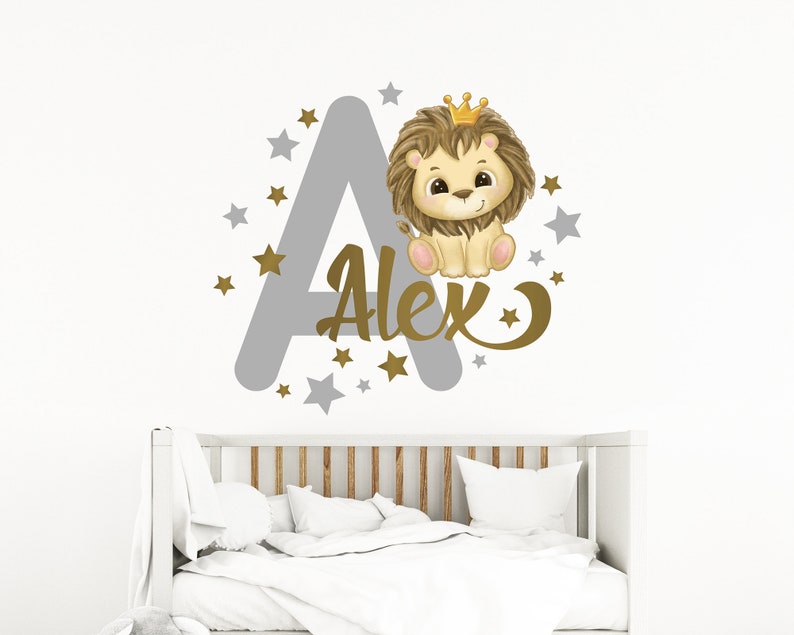 May include: A gray letter A with gold stars and a gold crown on top. A cute lion wearing a gold crown is sitting on the letter. The name Alex is written in gold cursive letters below the lion.