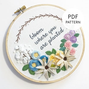 May include: Embroidered hoop art with a floral design and the text "Bloom where you are planted".
