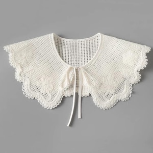 May include: White crochet collar with a scalloped edge and a tie at the neck.