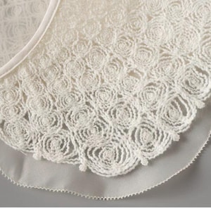May include: A white lace collar with a scalloped edge. The lace is made of delicate floral designs.