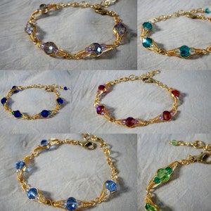 Könnte beinhalten: Sechs goldfarbene, drahtgewickelte Armbänder mit unterschiedlichfarbigen Kristallperlen. Die Armbänder zeichnen sich durch ein filigranes, kunstvolles Design mit kleinen, facettierten Kristallen aus.