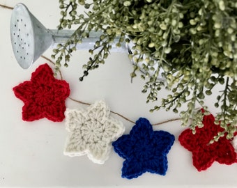 May include: A red, white, and blue crocheted star garland. The garland is strung on twine and features five stars in each color.