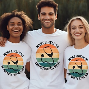 Puede incluir: Tres camisetas blancas con un diseño retro que presenta un estetoscopio y el texto "Most Likely To". El texto en las camisetas dice "Most Likely To Be The Vein Whisperer", "Most Likely To Leave Work AMA" y "Most Likely To Be Salty Like NS".